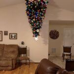 Upside-down decorated Christmas tree hanging from the ceiling in a living room.