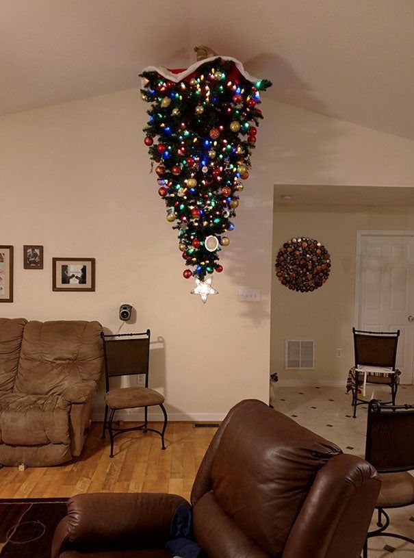 Upside-down decorated Christmas tree hanging from the ceiling in a living room.