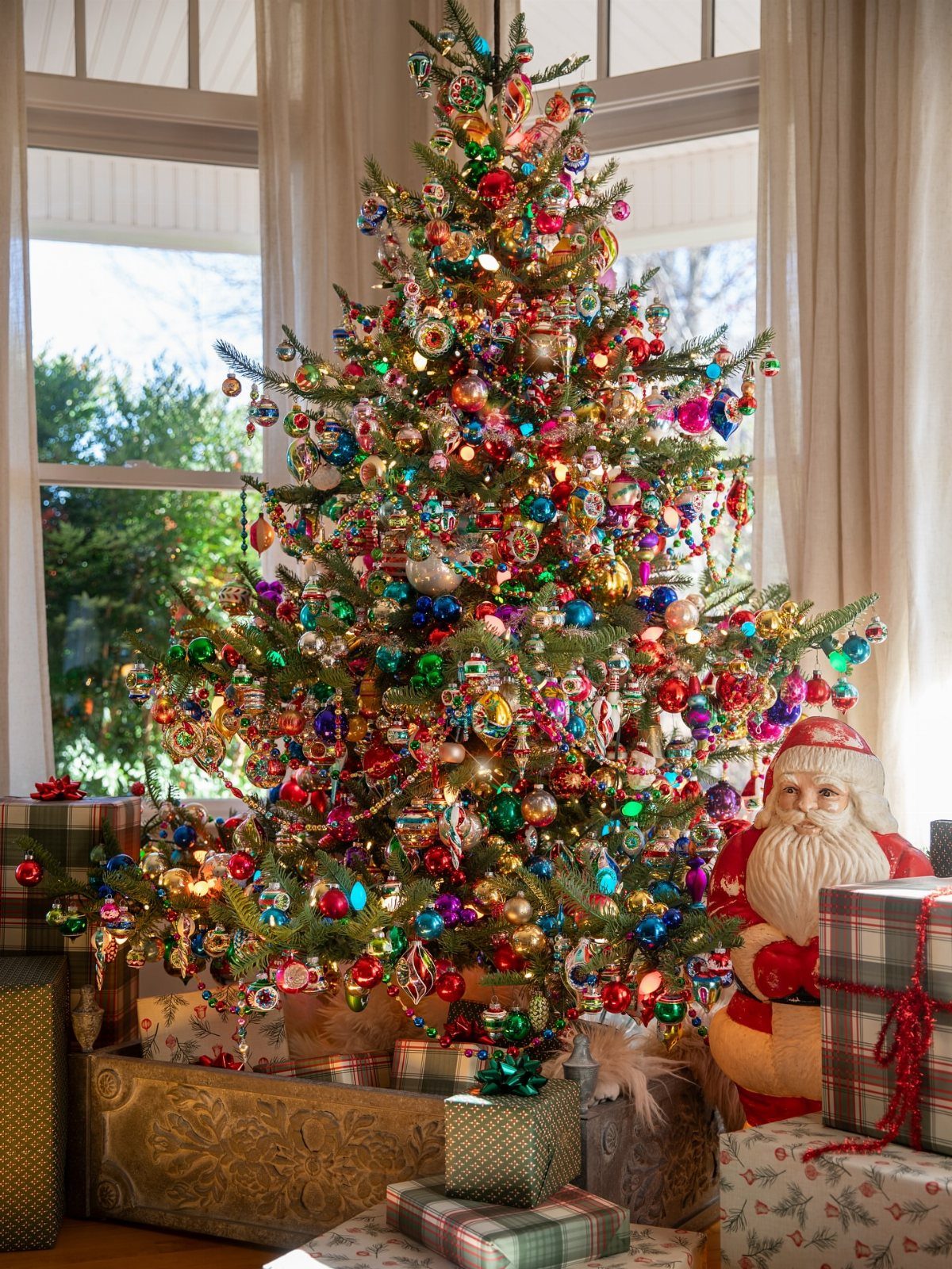 A decorated Christmas tree with colorful ornaments and lights surrounded by wrapped gifts.
