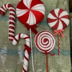 Red and white glittery decorative lollipops and candy canes on sticks lying on a green background.