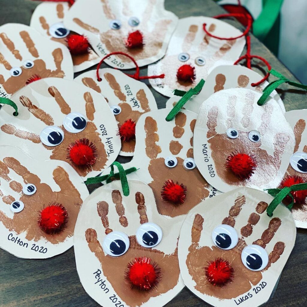 Handprint ornaments decorated with googly eyes, red pom-poms, and names written in black ink.
