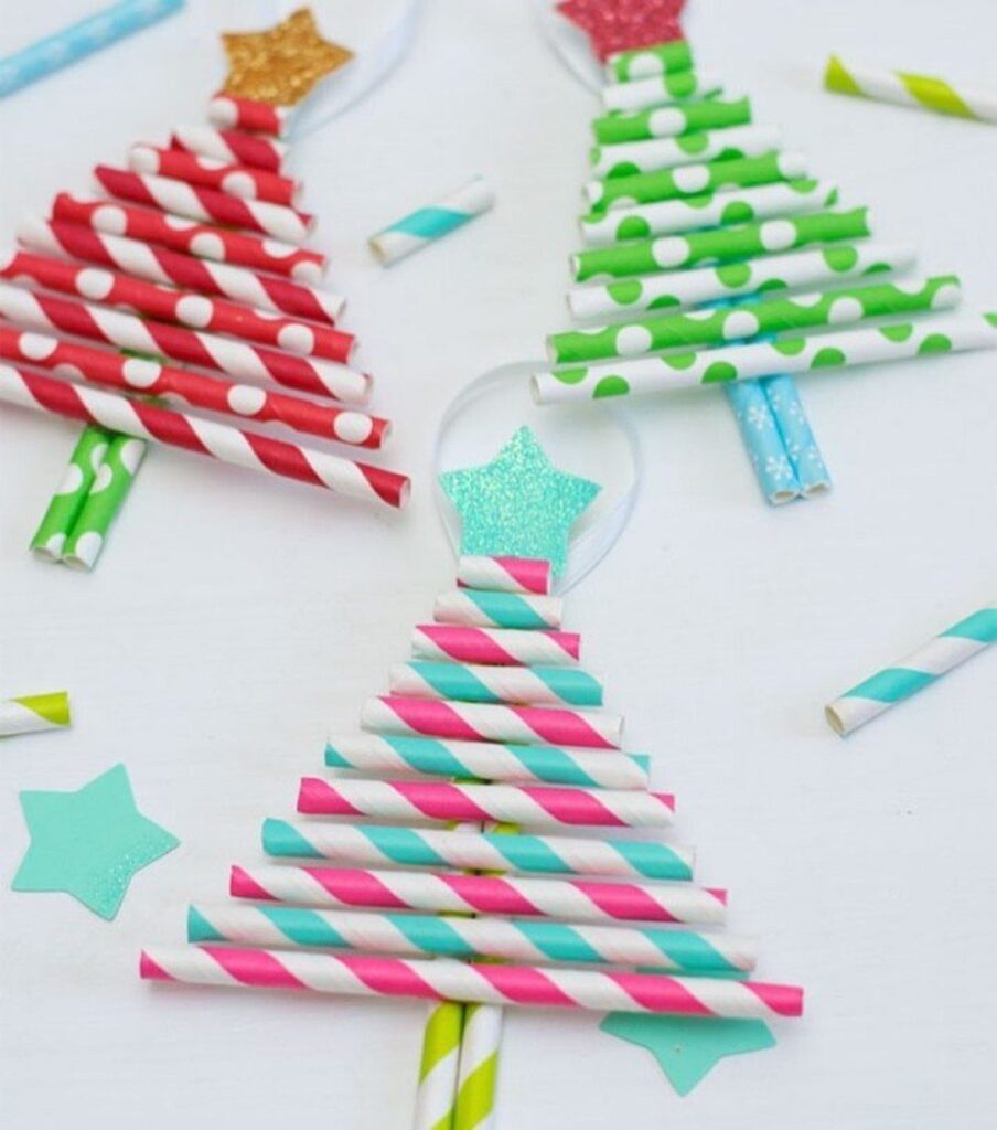 Three small Christmas trees constructed from colorful patterned paper straws with glittery star toppers.