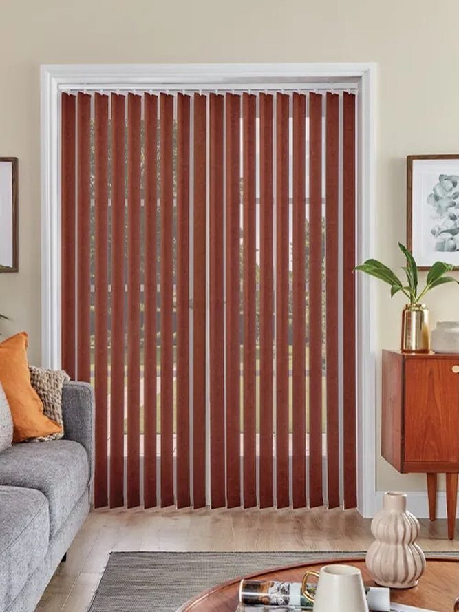 Red vertical blinds hanging over a large glass door in a modern living room setting.